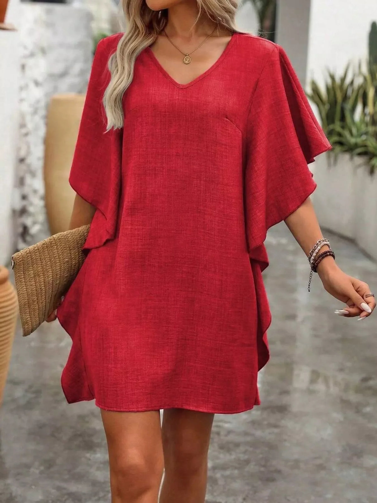 Woman wearing a flutter-sleeve V-neck mini dress outdoors
