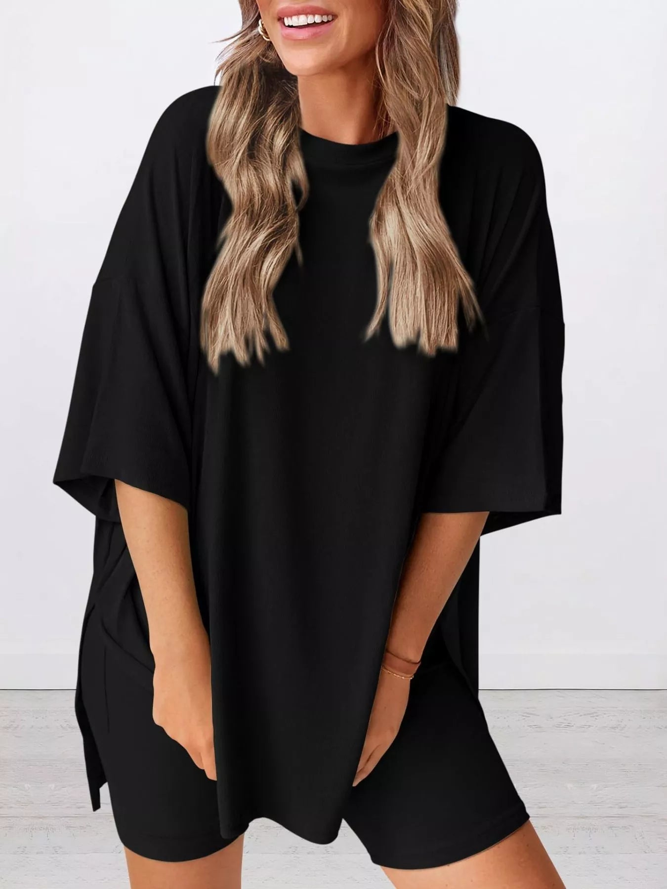 Woman wearing oversized black t-shirt and matching shorts in a minimal indoor setting