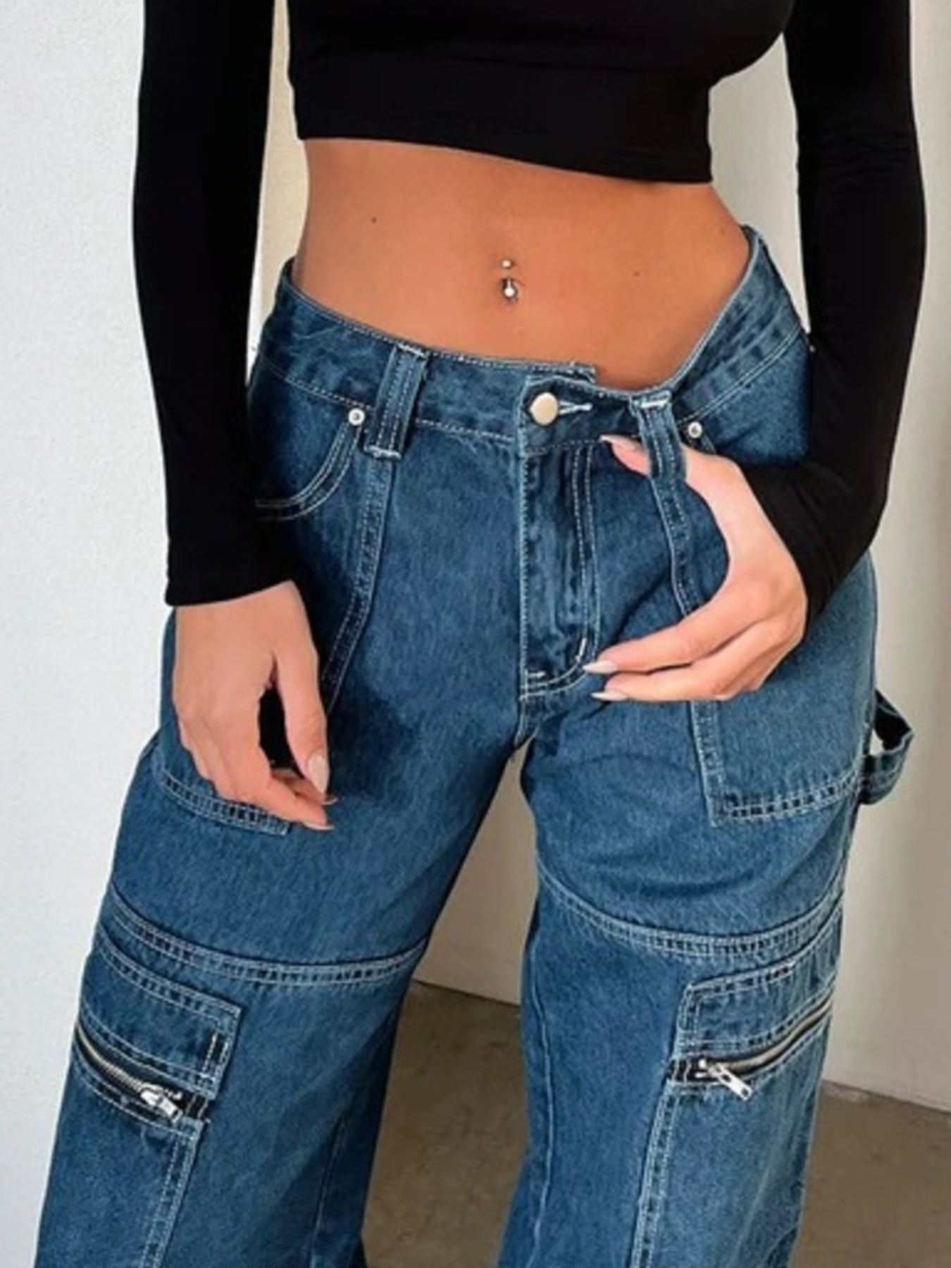 Woman wearing high-waisted cargo jeans with zipper details and black crop top