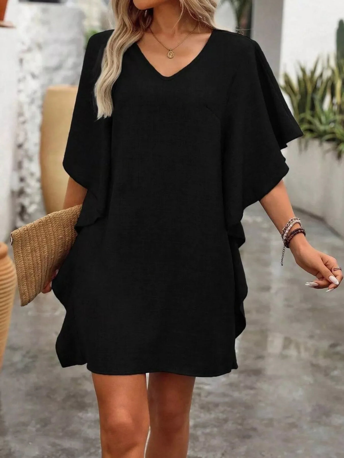 Woman wearing a ruffled flutter-sleeve V-neck mini dress