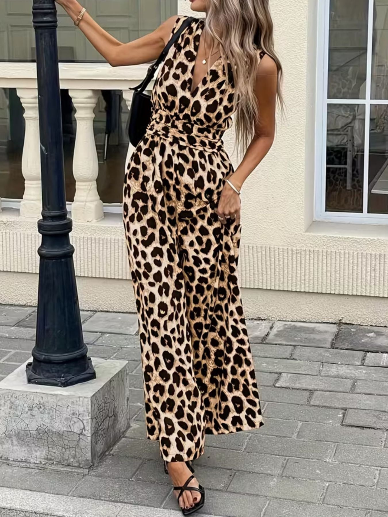 Woman wearing a sleeveless leopard print jumpsuit and sandals outdoors