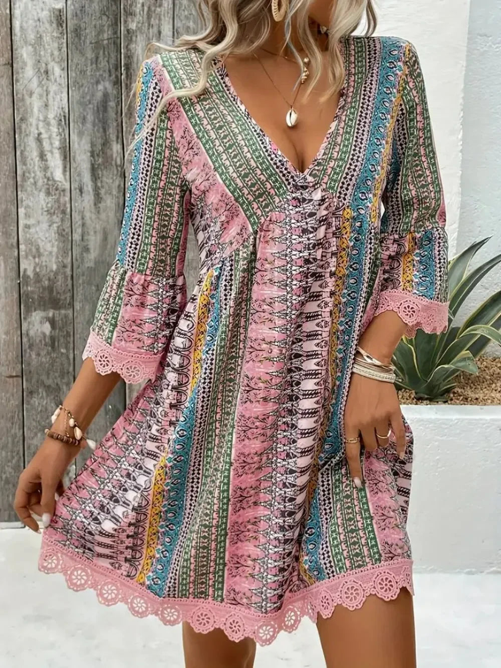 Woman wearing a boho print v-neck mini dress with lace trim, colorful patterns, and 3/4 sleeves.