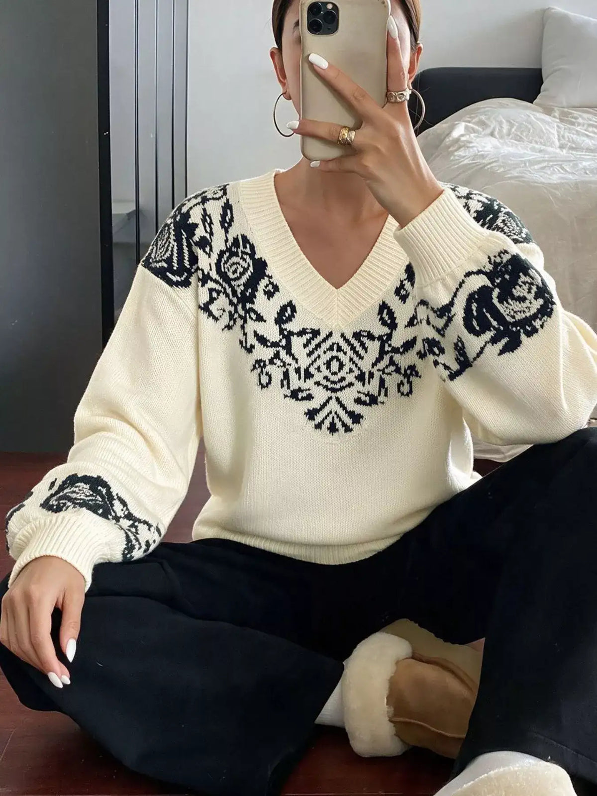 Woman wearing an Evie's Dreamland cream V-neck dropped shoulder sweater with black floral patterns.