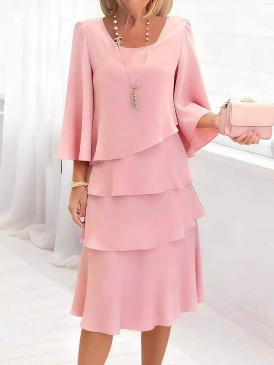 Pink ruffle tiered dress with bell sleeves, paired with matching clutch and layered necklace for elegant everyday style.