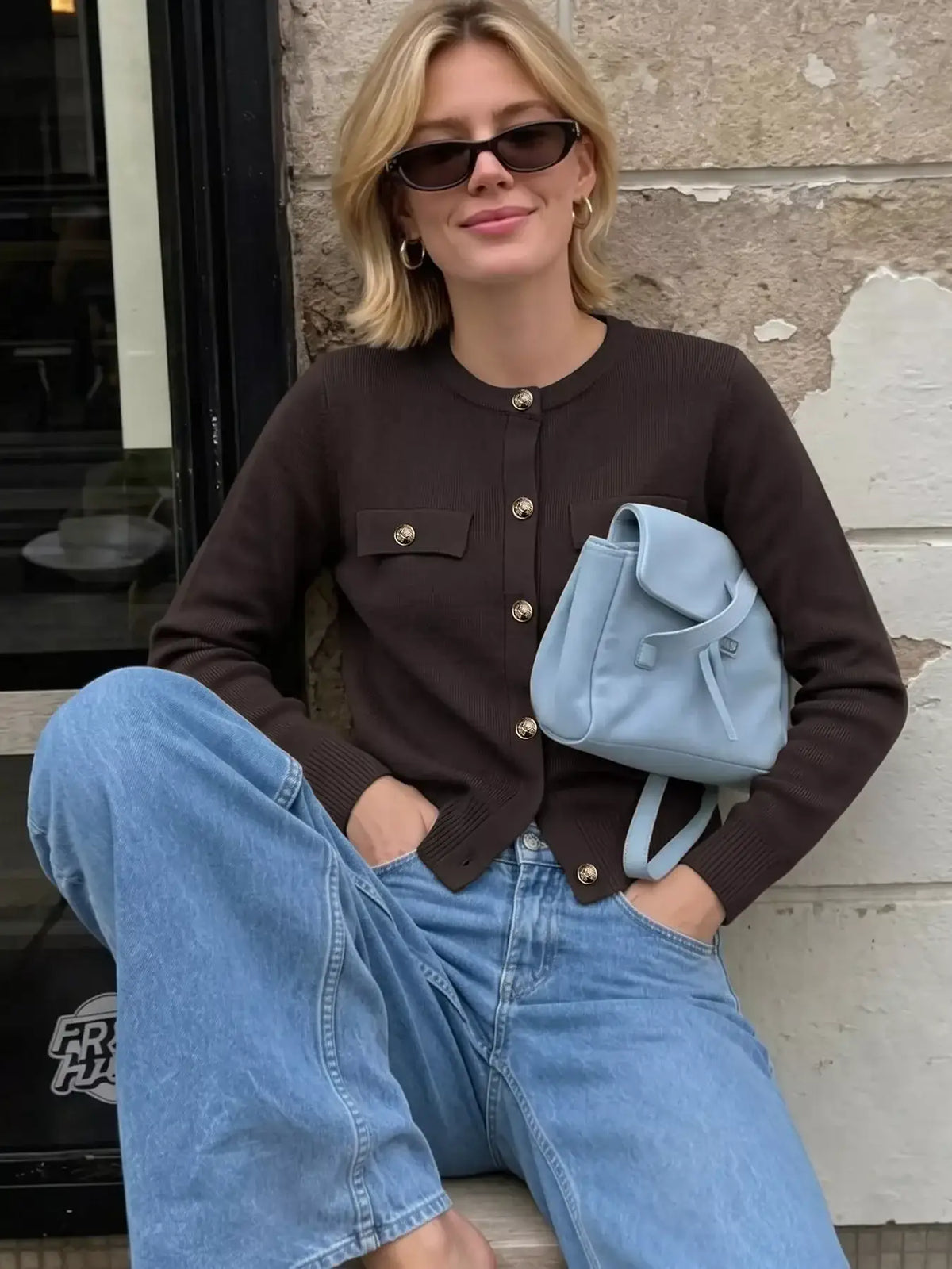 Woman wearing a brown long sleeve button down cardigan by Evie's Dreamland with blue jeans.