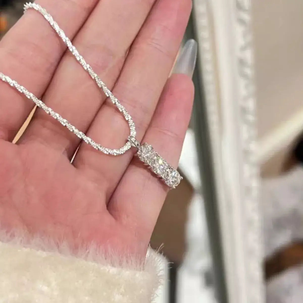 Evie's Dreamland Moissanite 925 sterling silver bar necklace with a sparkling stone pendant held in a hand.