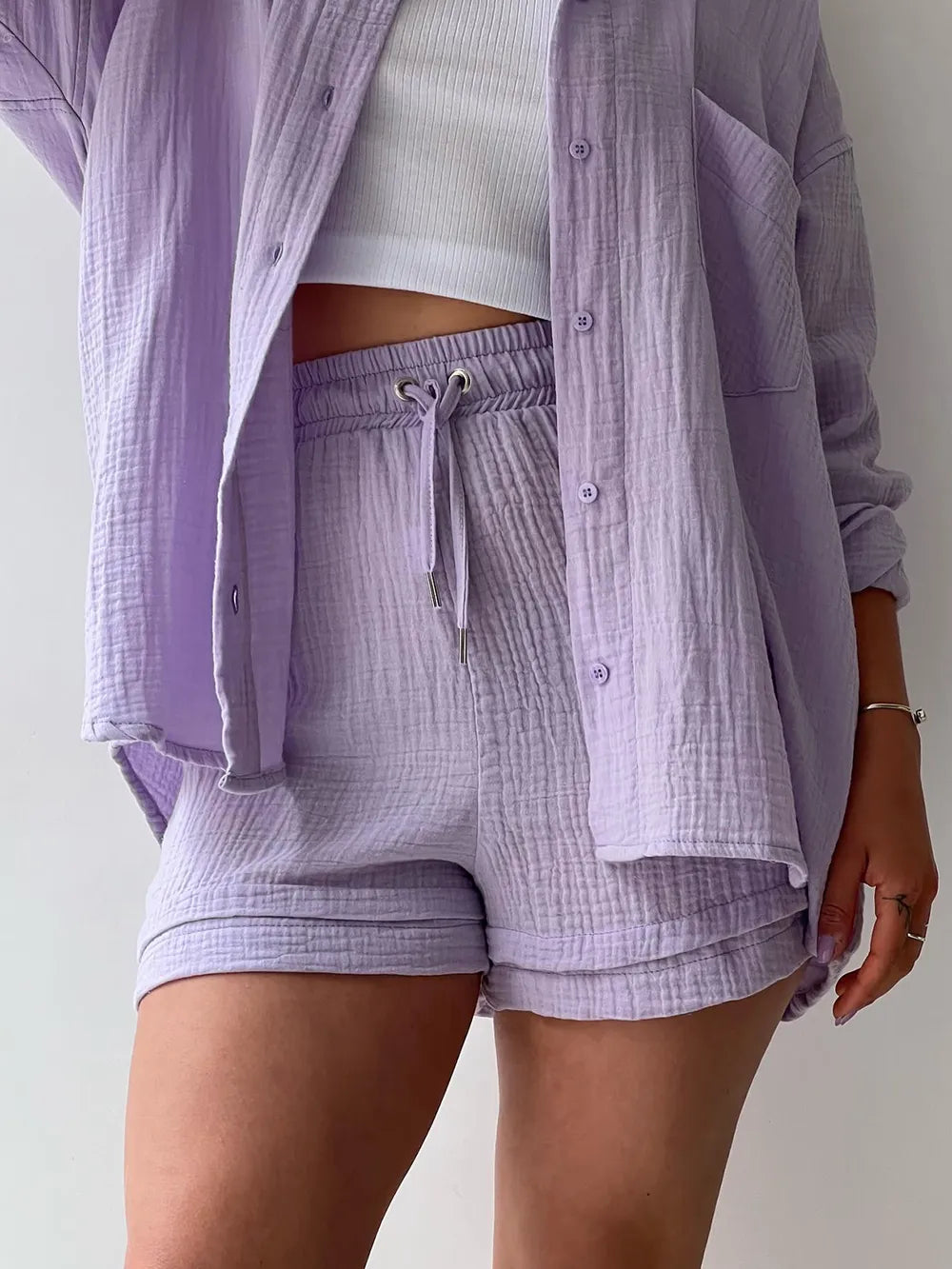 Woman wearing a lilac textured shirt and shorts set with a white ribbed crop top.