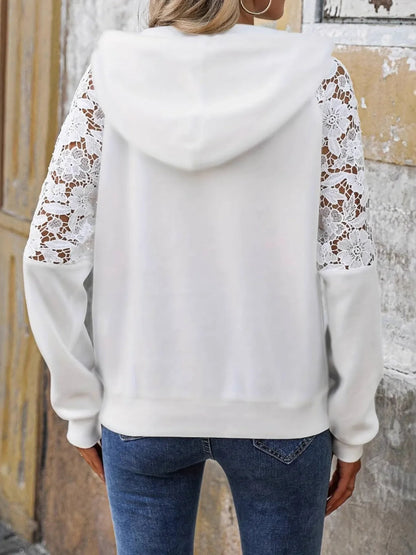 Back view of woman wearing white hoodie with floral lace sheer long sleeves and blue jeans
