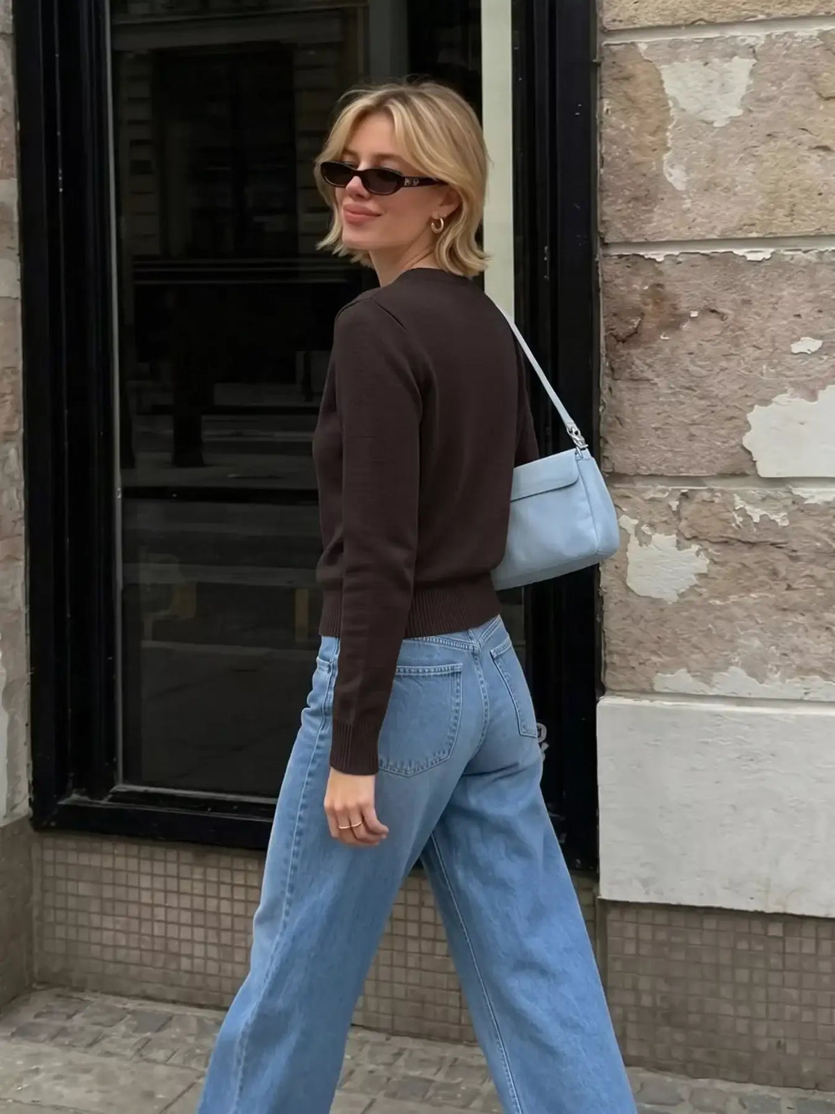 Woman wearing an Evie's Dreamland brown long sleeve knit cardigan paired with light wash wide-leg jeans.