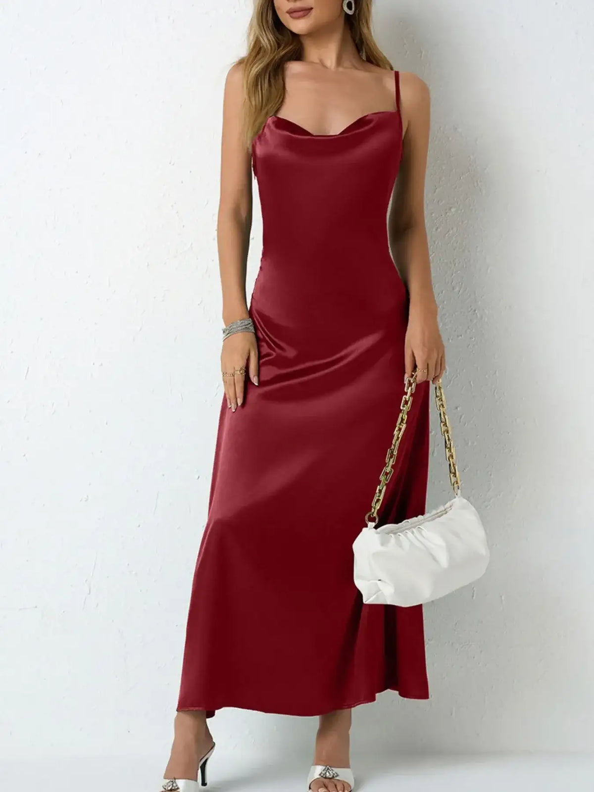 Woman wearing a red satin cowl neck slip maxi dress by Evie's Dreamland with a white handbag.