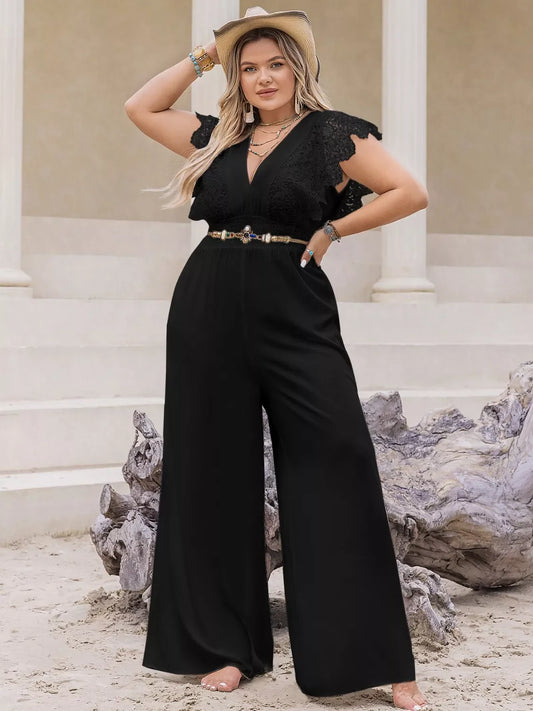 Plus size woman wearing black lace sleeve jumpsuit with wide legs and hat on sandy outdoor steps