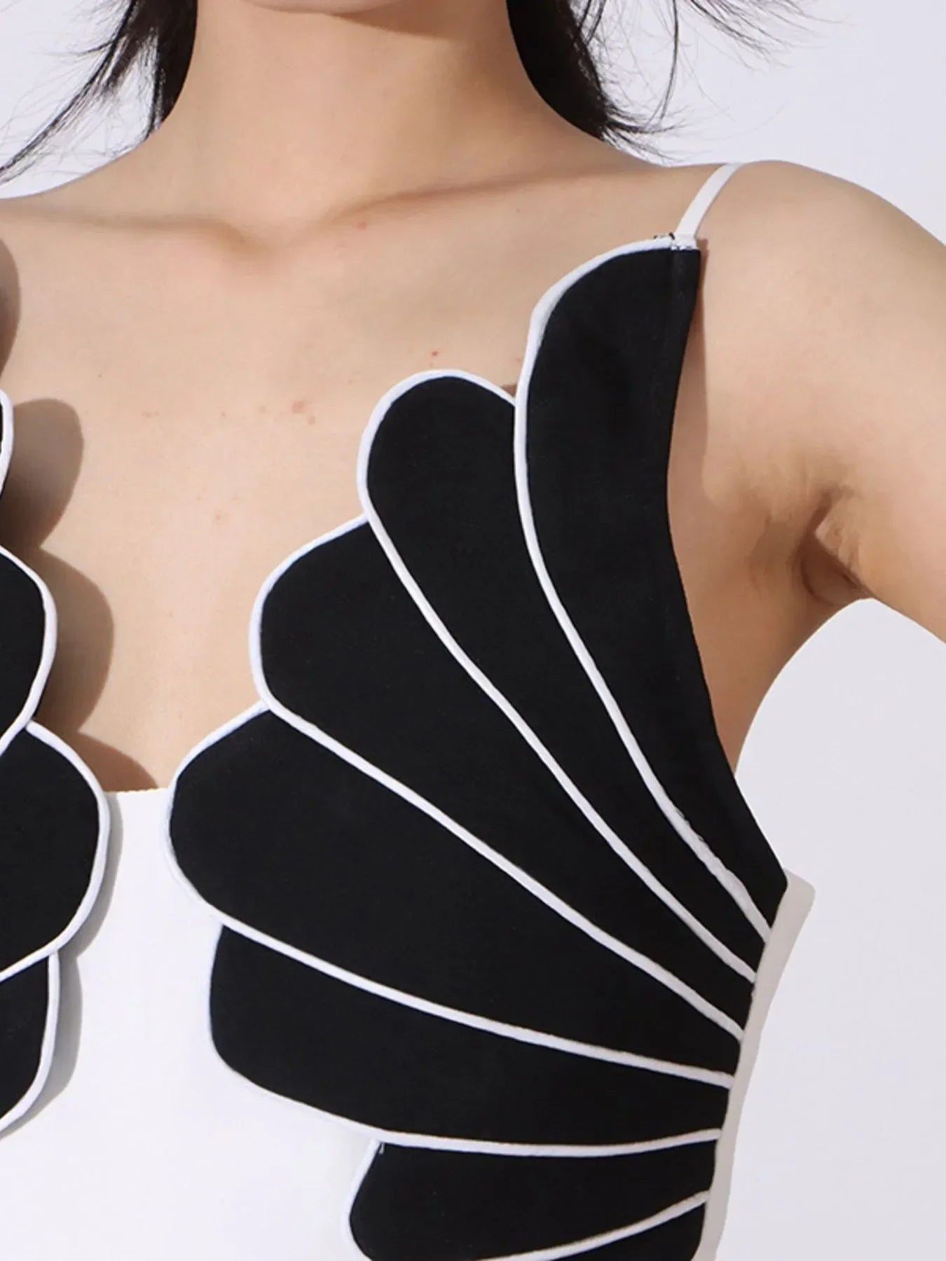 Close-up of black and white scallop-edge sleeveless top with thin straps on model