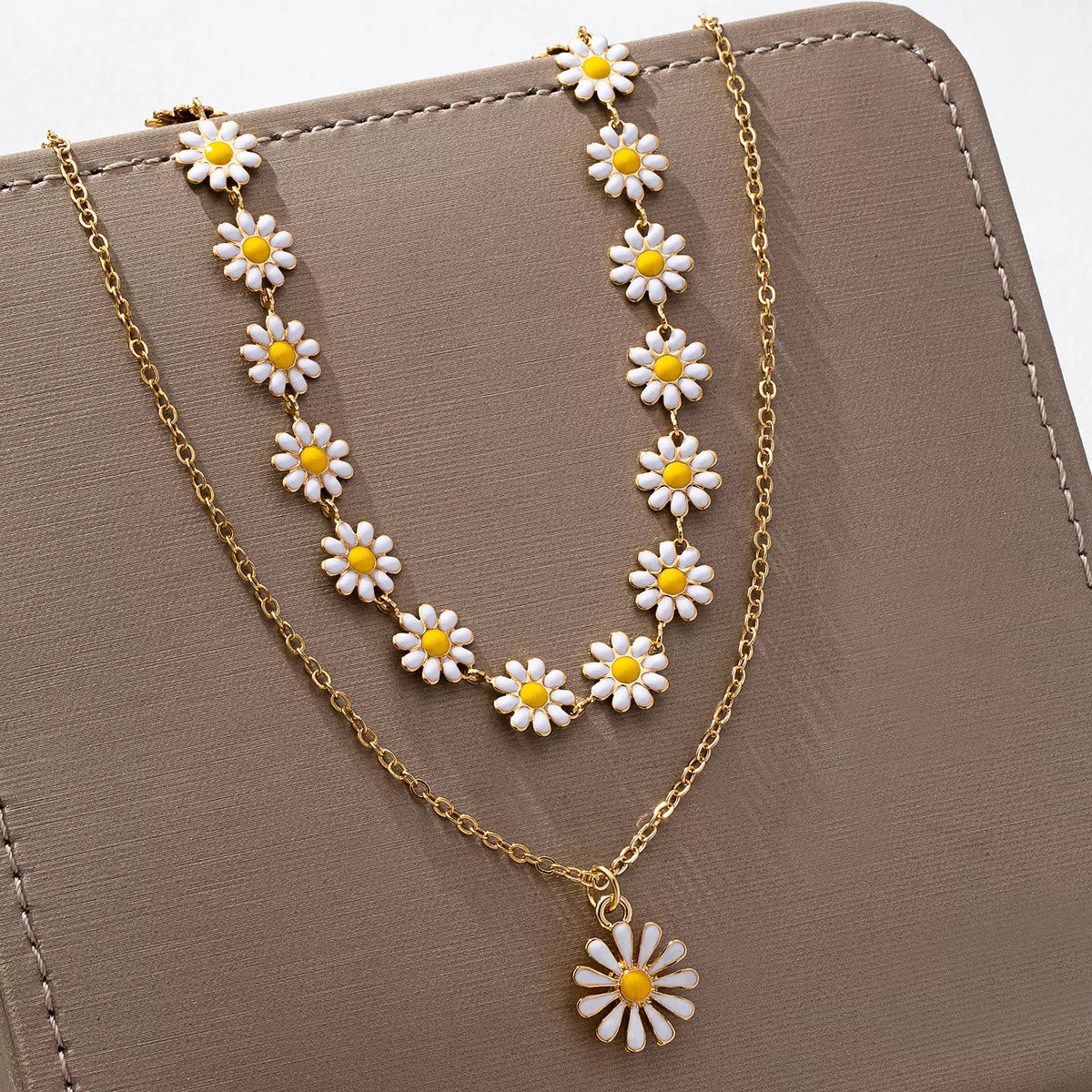 Gold chain necklace with white daisy flowers and yellow centers, layered style for everyday elegance