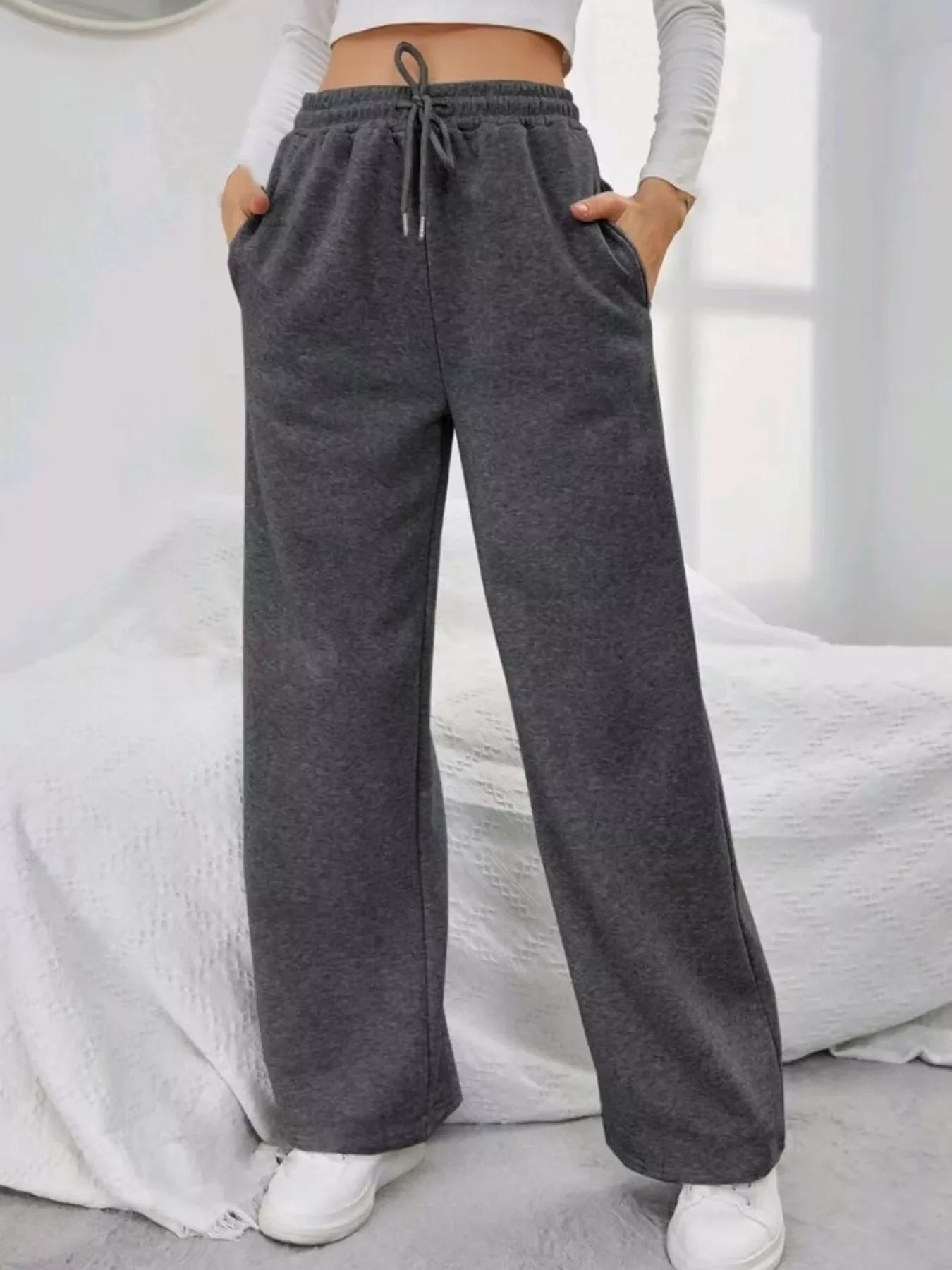 Woman wearing dark gray wide-leg sweatpants with drawstring waist and pockets