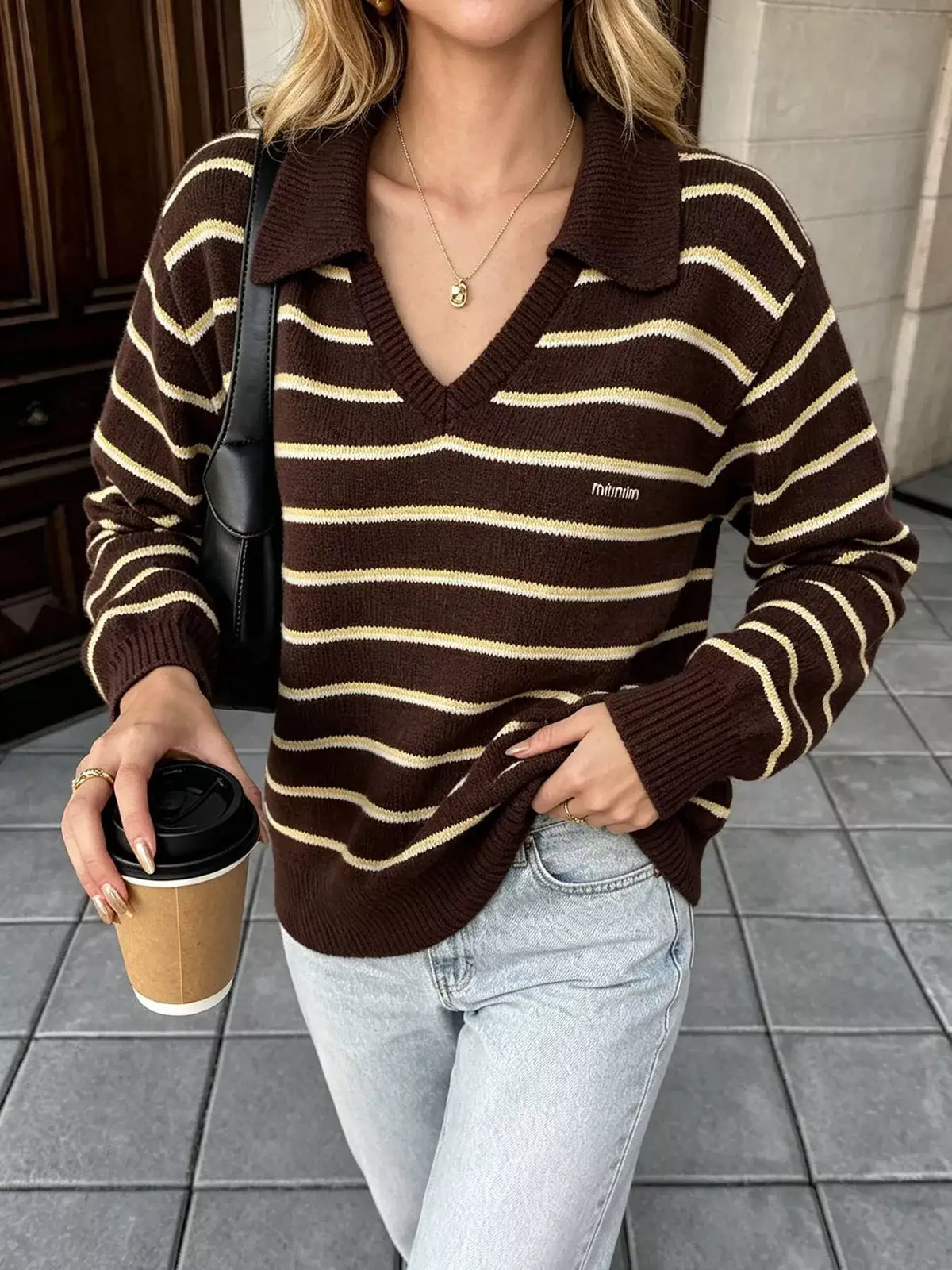 Woman wearing an Evie's Dreamland brown and beige striped polo collar sweater with light blue jeans.