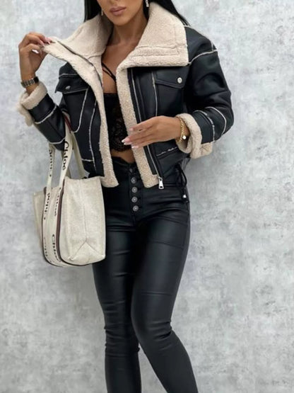 Woman wearing black faux leather jacket with cream shearling lining and black high-waisted leather pants holding beige tote bag