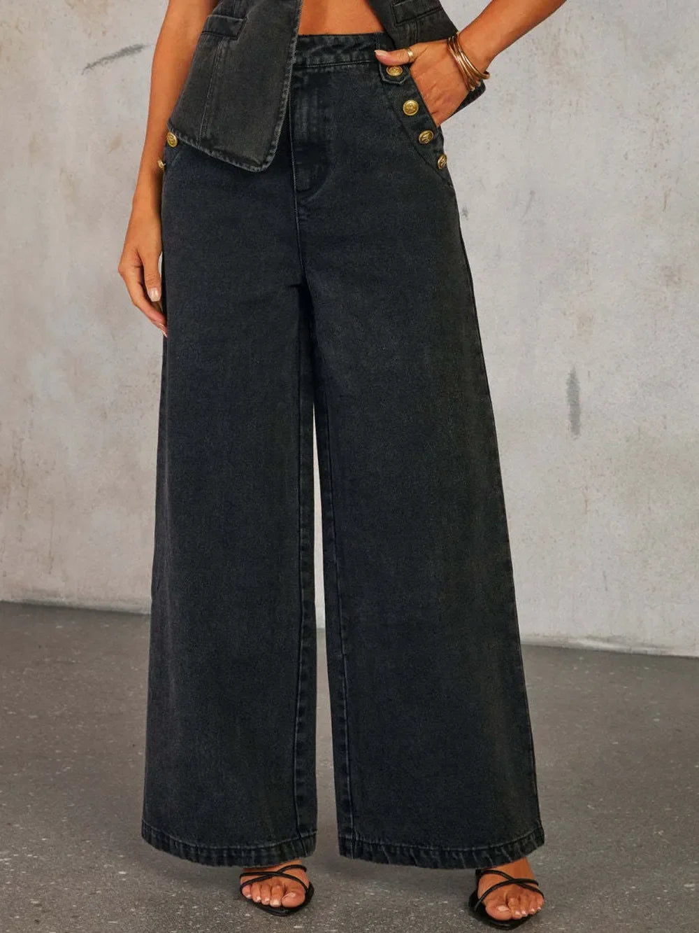 High-waisted black wide leg denim jeans with gold button details, trendy fashion style