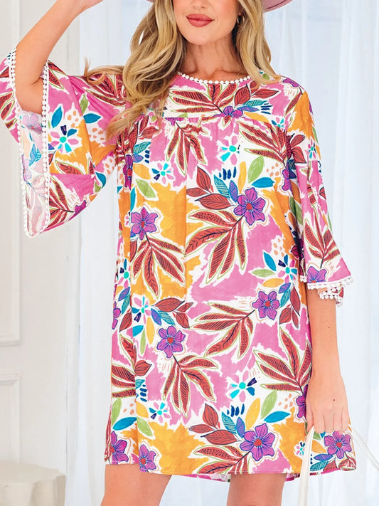 Woman wearing a colorful floral print dress with bell sleeves and white trim