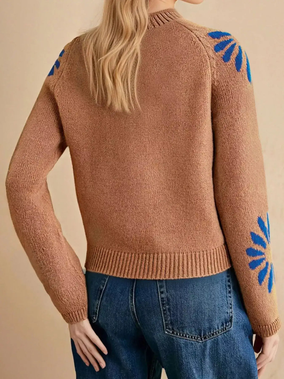 Back view of a brown Evie's Dreamland mock neck raglan sweater with blue floral embroidery on sleeves.
