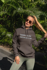Woman wearing a hoodie with 'Grippy Sock Vacation Club' text in a tropical setting