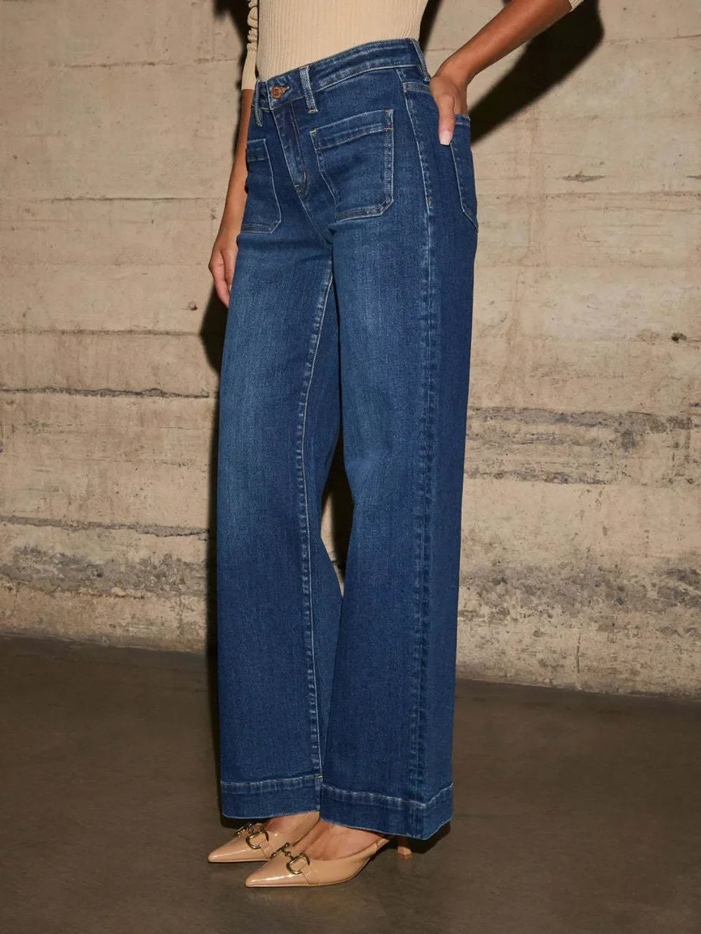Woman wearing high-waisted wide leg blue jeans with front pockets and beige heels