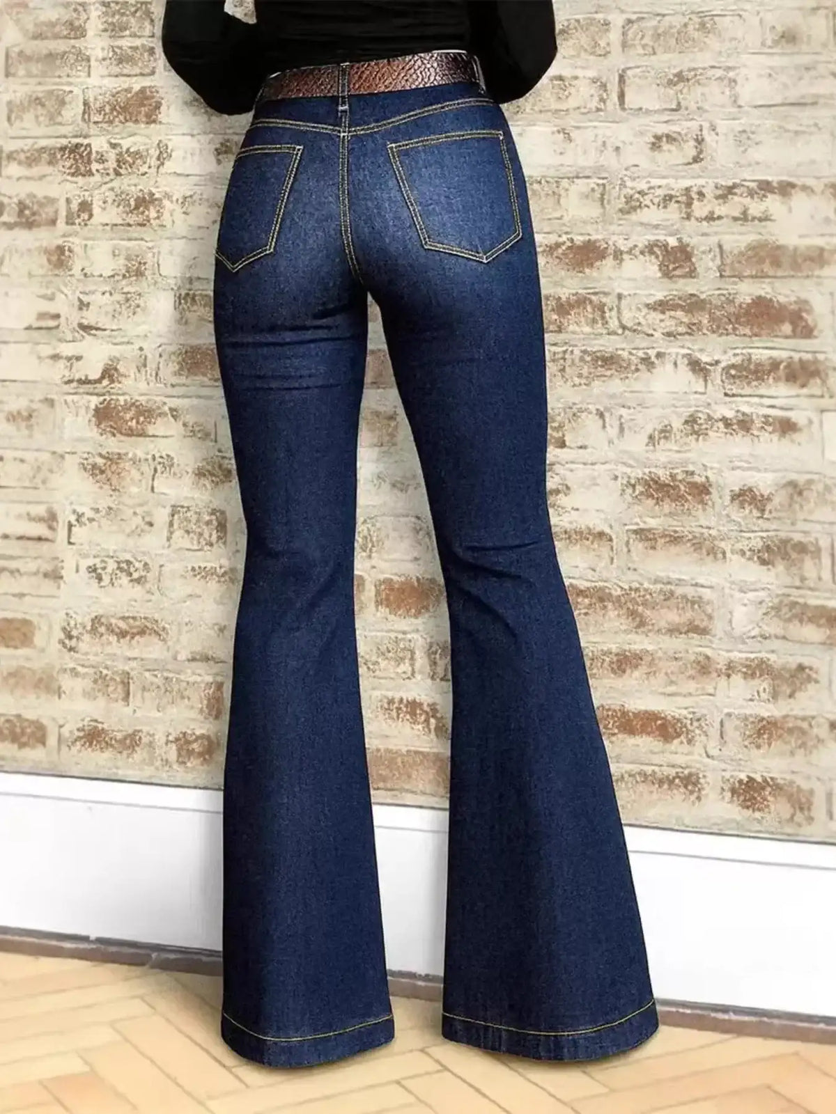 Back view of women's dark wash high-waisted flare jeans with a brown belt.